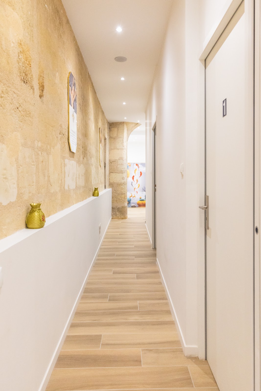 Passage intérieur aux murs de pierre beige menant vers les salles